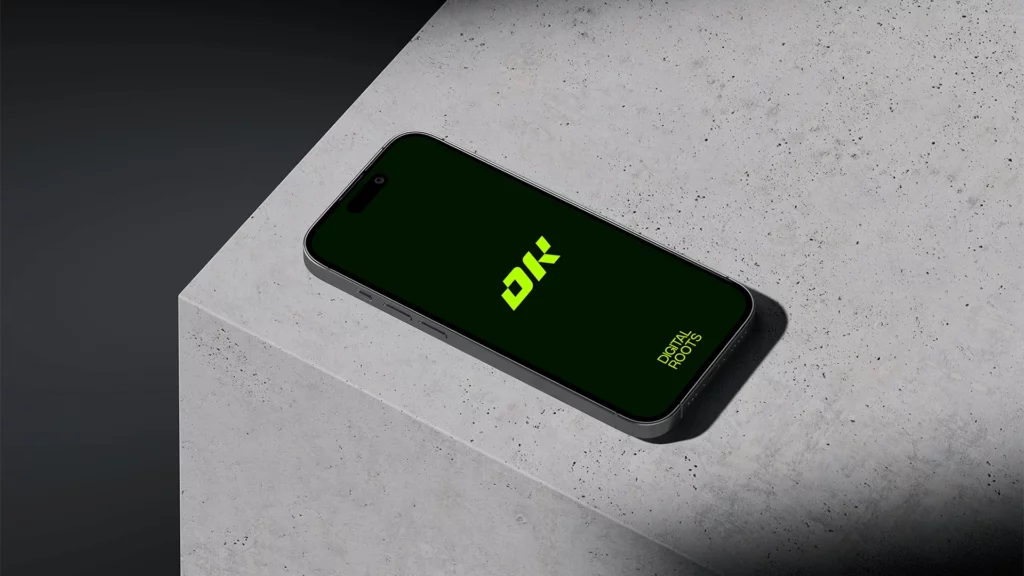Téléphone posé sur surface en béton avec logo Digital Roots vert.